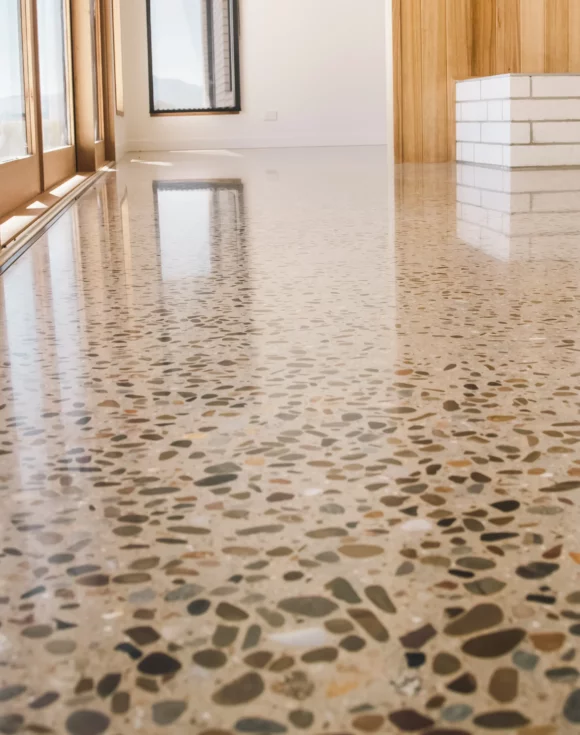 Polished terrazzo floor with colorful stone chips, reflecting natural light in a modern interior space with wooden accents